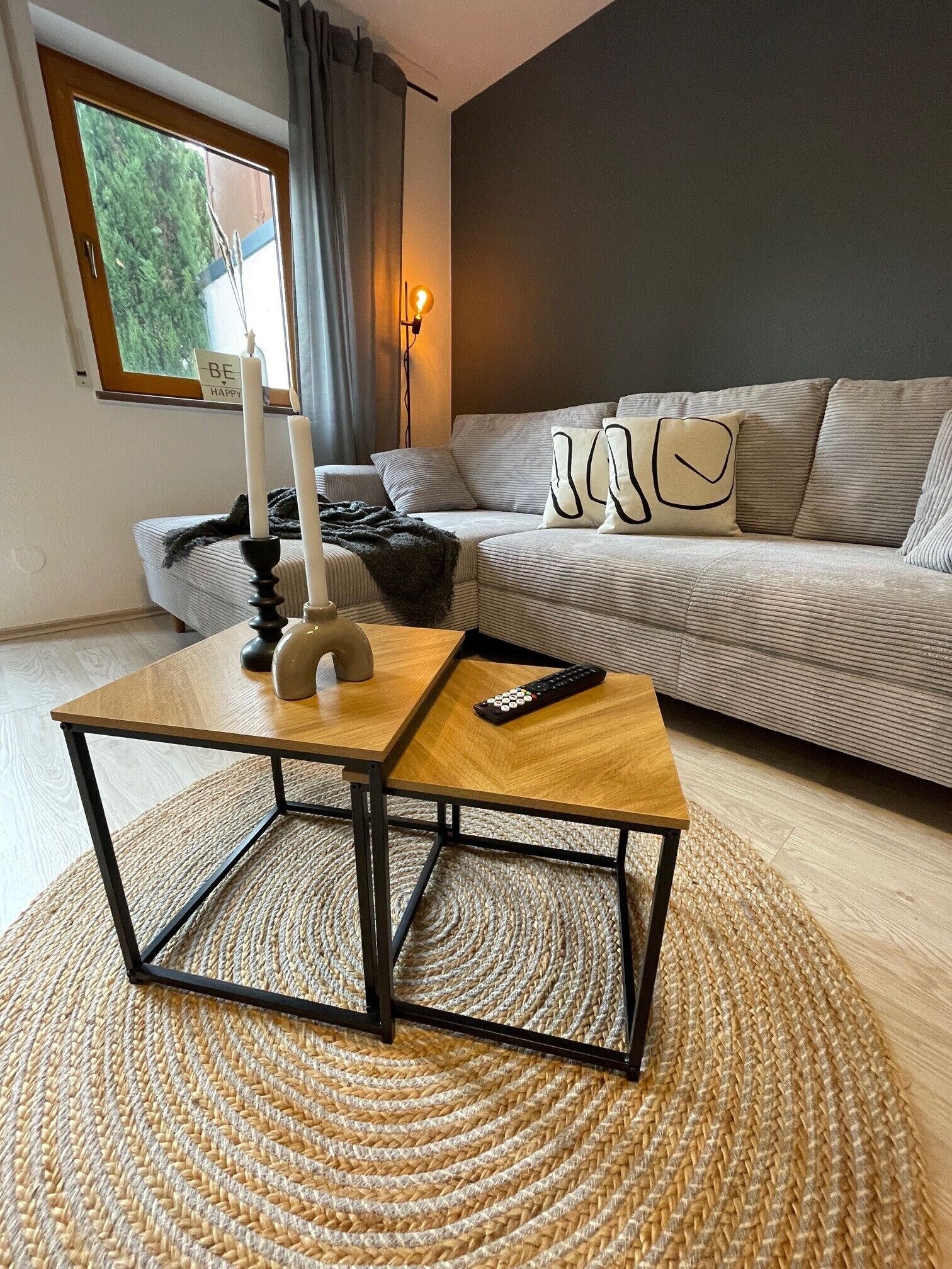 A living room with a sofa, a coffee table, a remote control, and a candle.