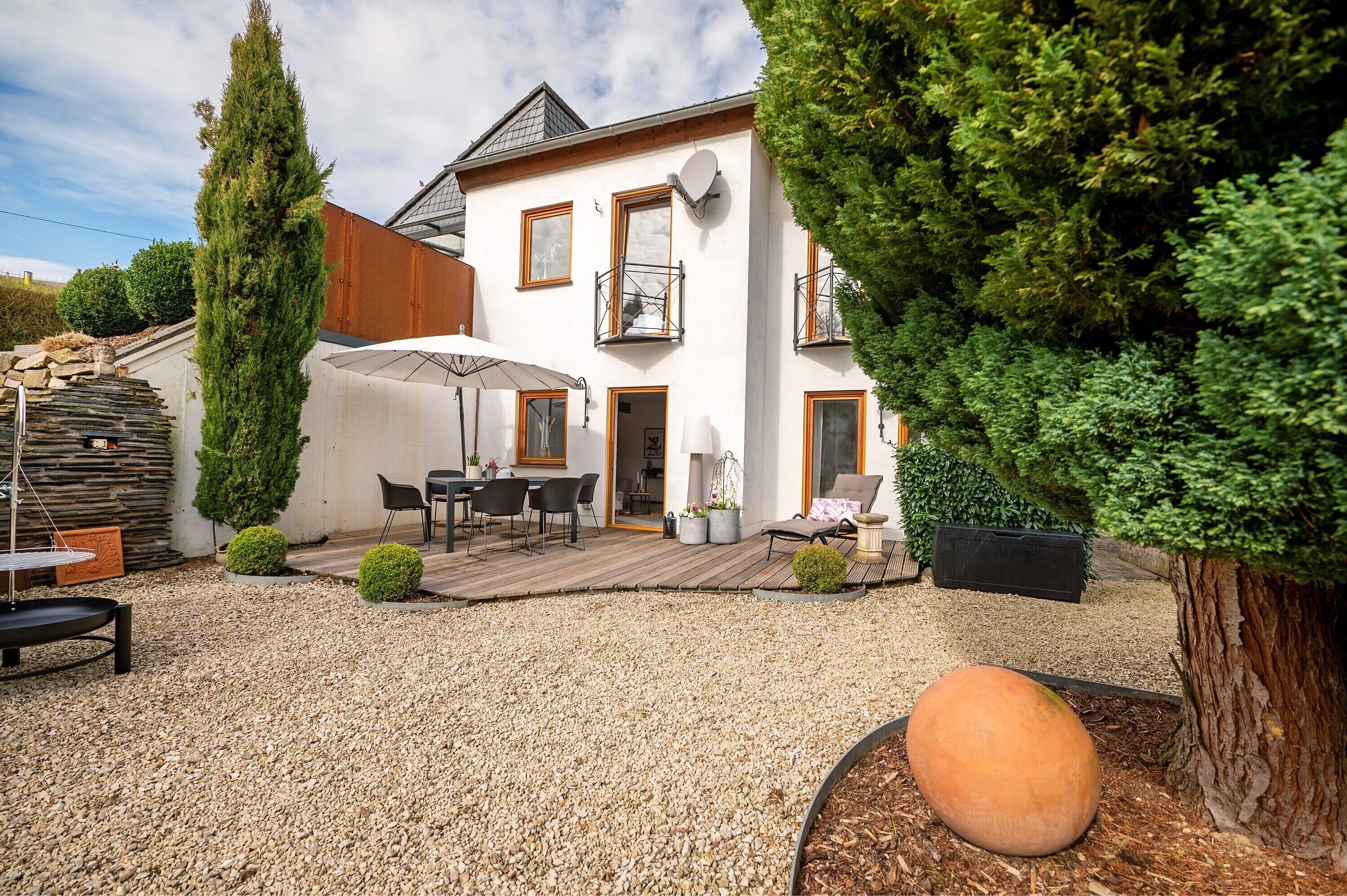 A house with a patio, outdoor furniture, and a large tree.