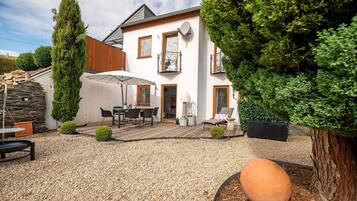 A house with a patio, outdoor furniture, and a large tree.