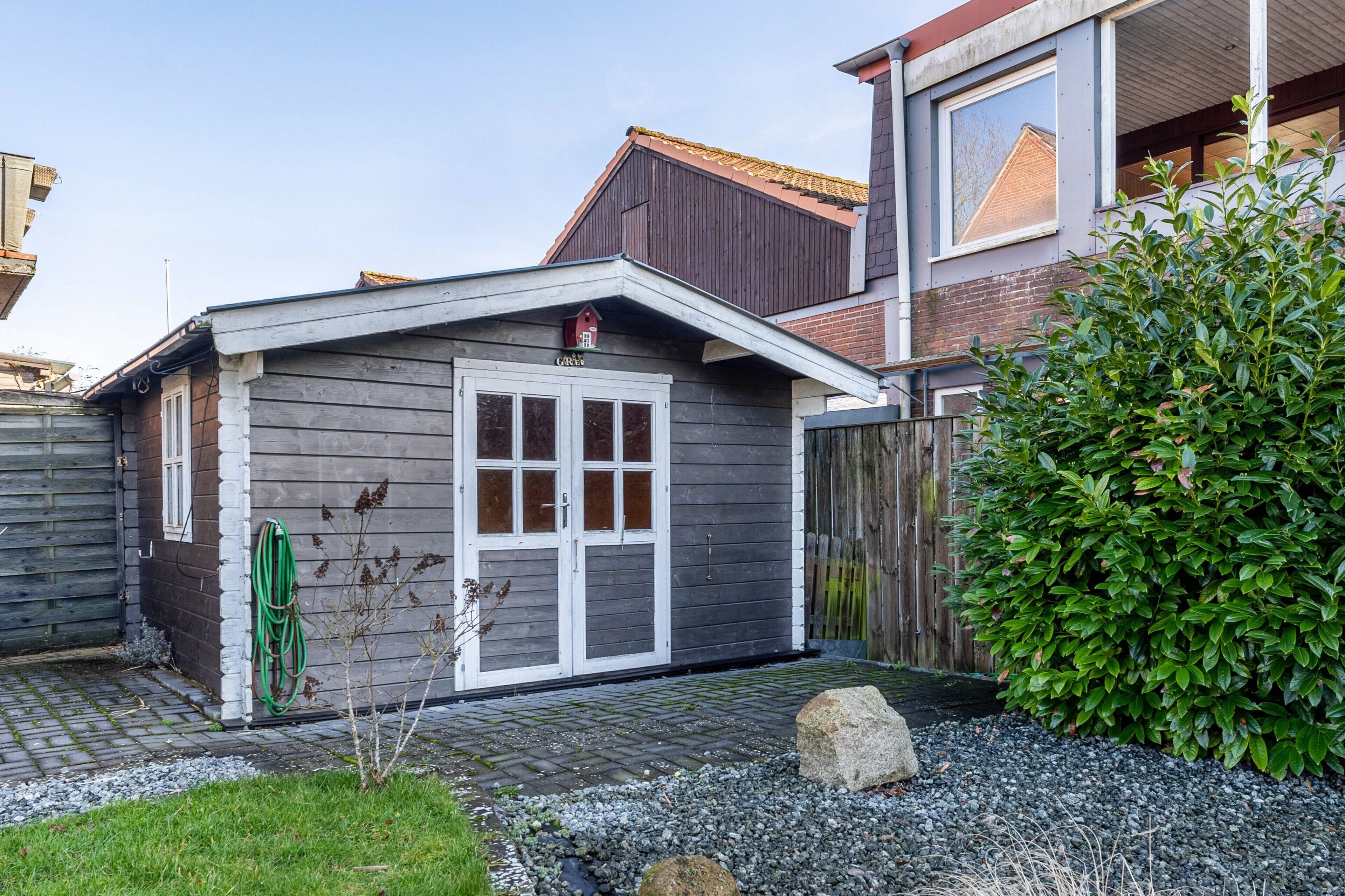 A residential building with a garage, a wooden fence, and a well-maintained garden.