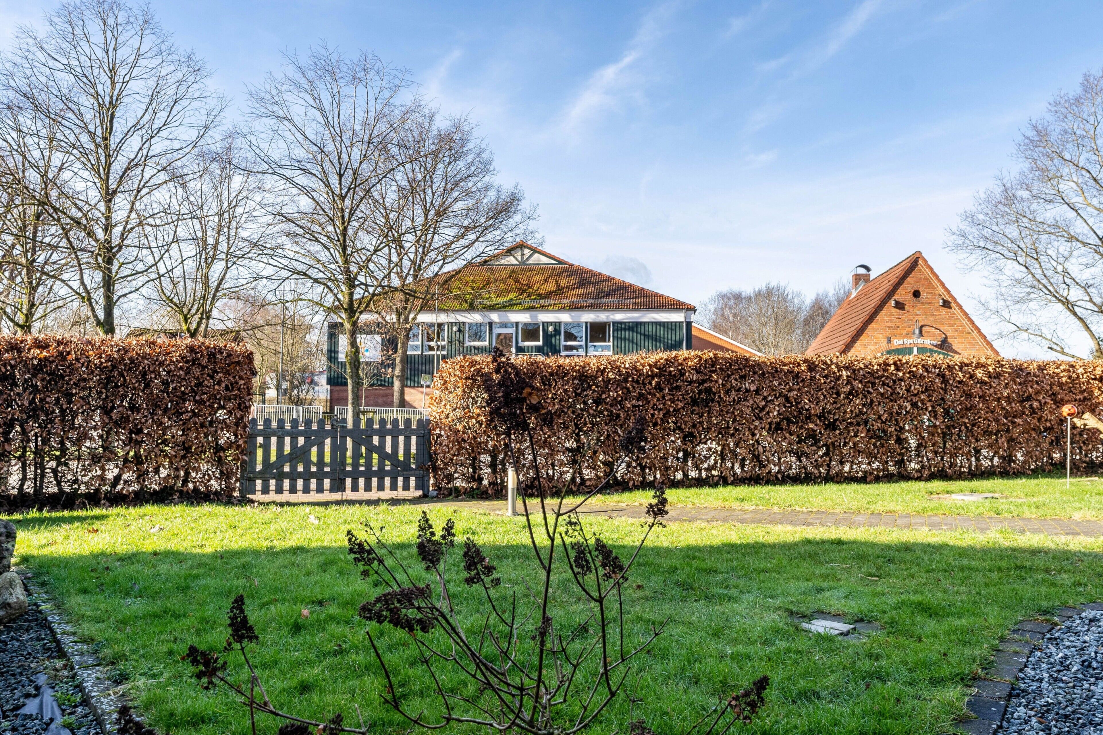 A residential property with a large glass conservatory, a traditional brick house, and a well-maintained garden.