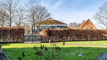 A residential property with a large glass conservatory, a traditional brick house, and a well-maintained garden.
