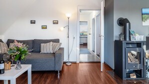 Un salon moderne avec un canapé gris, une table basse blanche, un lampadaire et un poêle à bois.