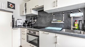 A modern kitchen with white cabinets, stainless steel appliances, and a grey countertop.