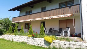 Un edificio su due piani con un balcone, parete in pietra e zona salotto all'aperto.