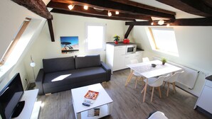 A compact living space with a sofa, a dining table with chairs, a kitchenette, and a TV. - Holiday Apartment 'Rheinblick Wohnung 5' with Shared Terrace, Wi-Fi and Air Conditioning (Koblenz)