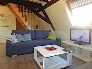 A living room with a sofa, a coffee table, a TV, and a staircase.