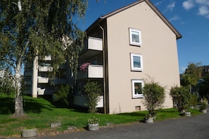 Un immeuble résidentiel à plusieurs étages, doté de balcons, d’un toit plat et surplombant un ciel dégagé.