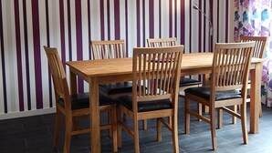 Ein Essbereich mit Holztisch und Stühlen, einer gestreiften Wand und einer Stehlampe.