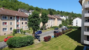 Ein Wohngebiet mit Mehrfamilienhäusern, einem Parkplatz und einer von Bäumen gesäumten Straße.