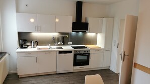 Cozinha moderna com armários brancos, lava-louças, fogão e cafeteira.