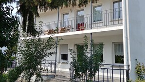 Um edifício com várias andares, varandas, um jardim e céu limpo.