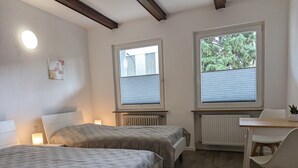Quarto com duas camas, uma escrivaninha e uma cadeira.