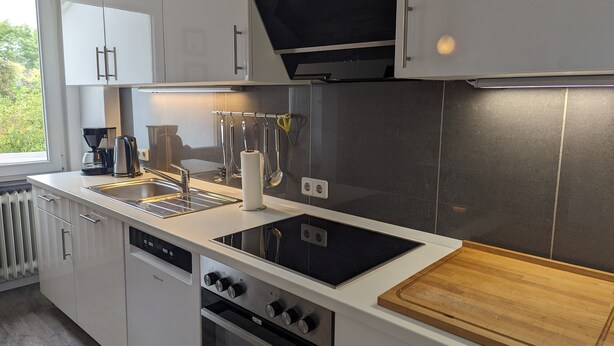 Uma cozinha moderna com forno embutido, fogão e tábua de corte de madeira.
