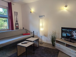 Un salon moderne avec un canapé, une lampe sur pied, un téléviseur et une petite table.