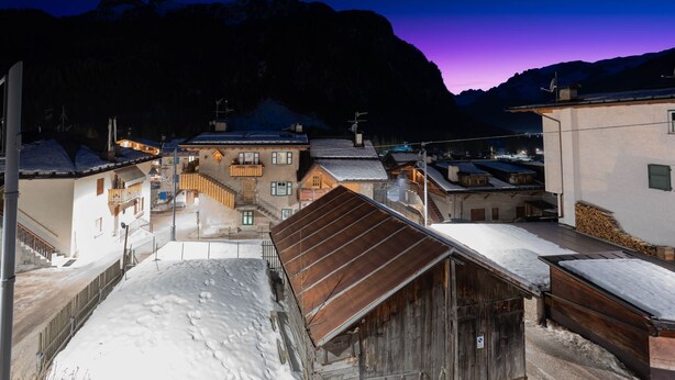 A snow-covered village with traditional wooden buildings and a mountain backdrop. - Beautiful, recently renovated flat (Canazei)