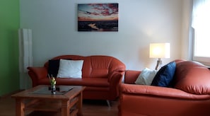 A living room with a sofa, a small table, and a lamp.