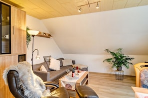 Una sala de estar moderna estilo loft, con techo inclinado, un sofá, sillones de cuero, una mesa de centro de madera y una planta en maceta.