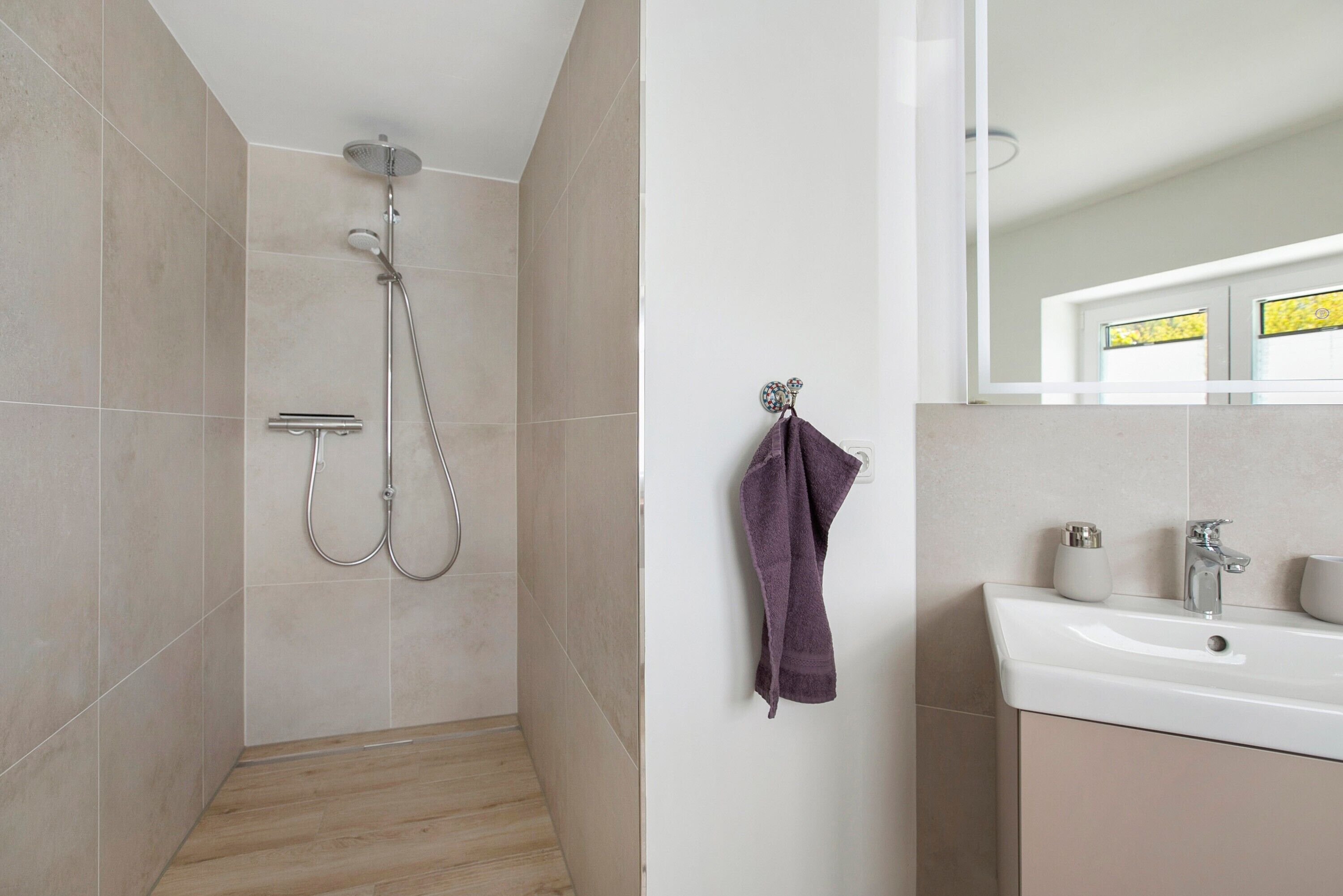 A bathroom with a shower, a sink, and a mirror.