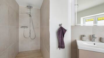 A bathroom with a shower, a sink, and a mirror.