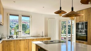 Une cuisine moderne avec des meubles en bois, un grand îlot central et une vue sur un quartier résidentiel.