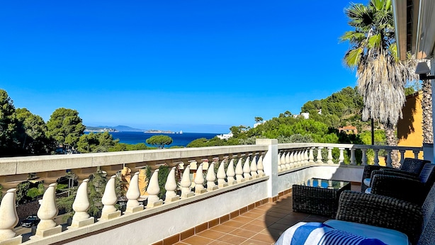 Un balcon avec vue sur la mer, un sol carrelé et du mobilier d’extérieur.