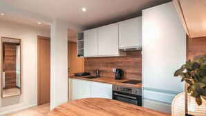 A modern kitchen with white cabinets, a wooden countertop, and a built-in oven. - Modern 2BR 2BTH | Hypercenter | Croisette | AC (Cannes)