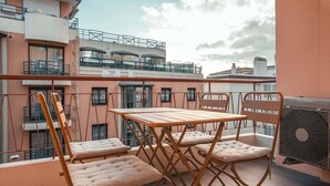 A balcony with a wooden table and chairs, a fan, and a view of surrounding buildings. - Modern 2BR 2BTH | Hypercenter | Croisette | AC (Cannes)