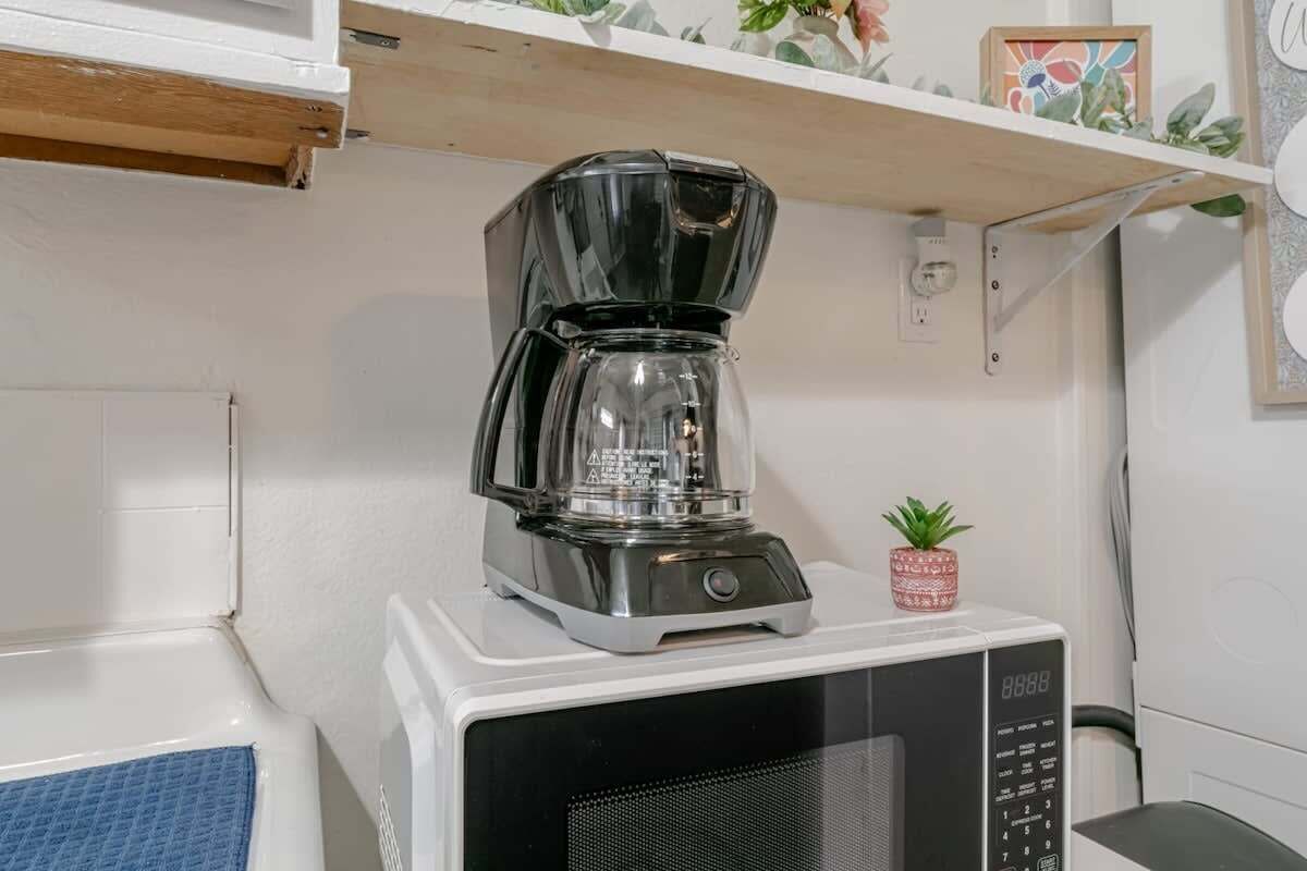 A kitchen with a microwave and a coffee maker on top of it.