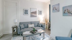A modern living room with a grey sofa, a coffee table, and framed artwork on the walls. - Charming Midtown Apt - Hannon Hideaway Unit B (Mobile)