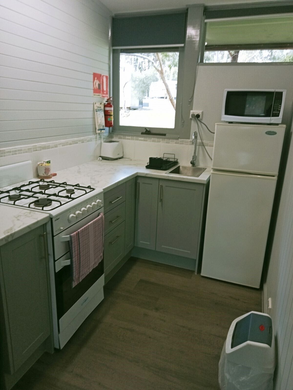 Una cocina compacta con estufa a gas, microondas, refrigerador y pileta.