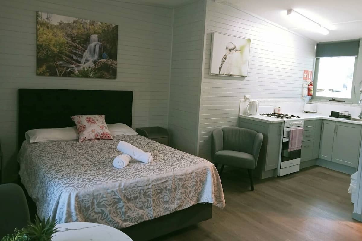 Une chambre comprenant un lit, une chaise, un bureau et un coin cuisine.