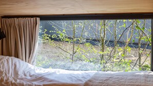 Un dormitorio con un ventanal grande, una cama y una cortina.