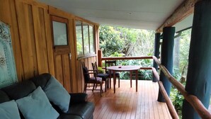 Una terraza de madera con un sofá de cuero negro y una mesa con sillas.