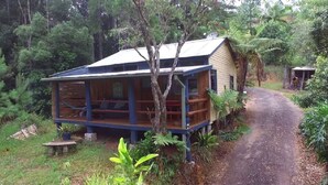 Una cabaña de madera con porche, rodeada de un bosque denso.