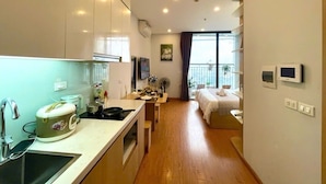 Une chambre d’hôtel compacte comprenant un coin cuisine, un lit, une petite salle de bain et un balcon avec vue.