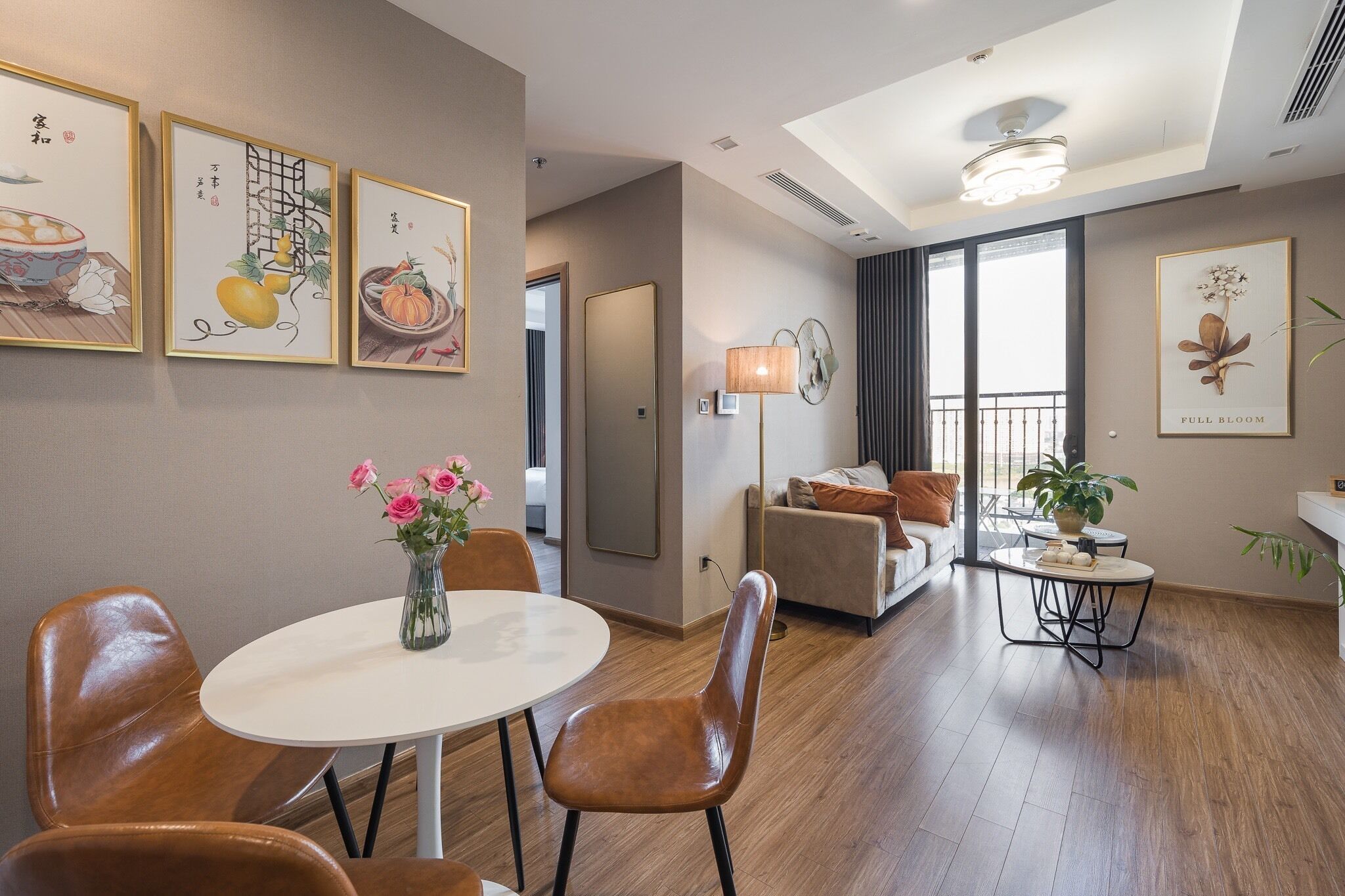 A modern living room with a dining area, featuring a sofa, a table with chairs, and framed artwork on the walls.