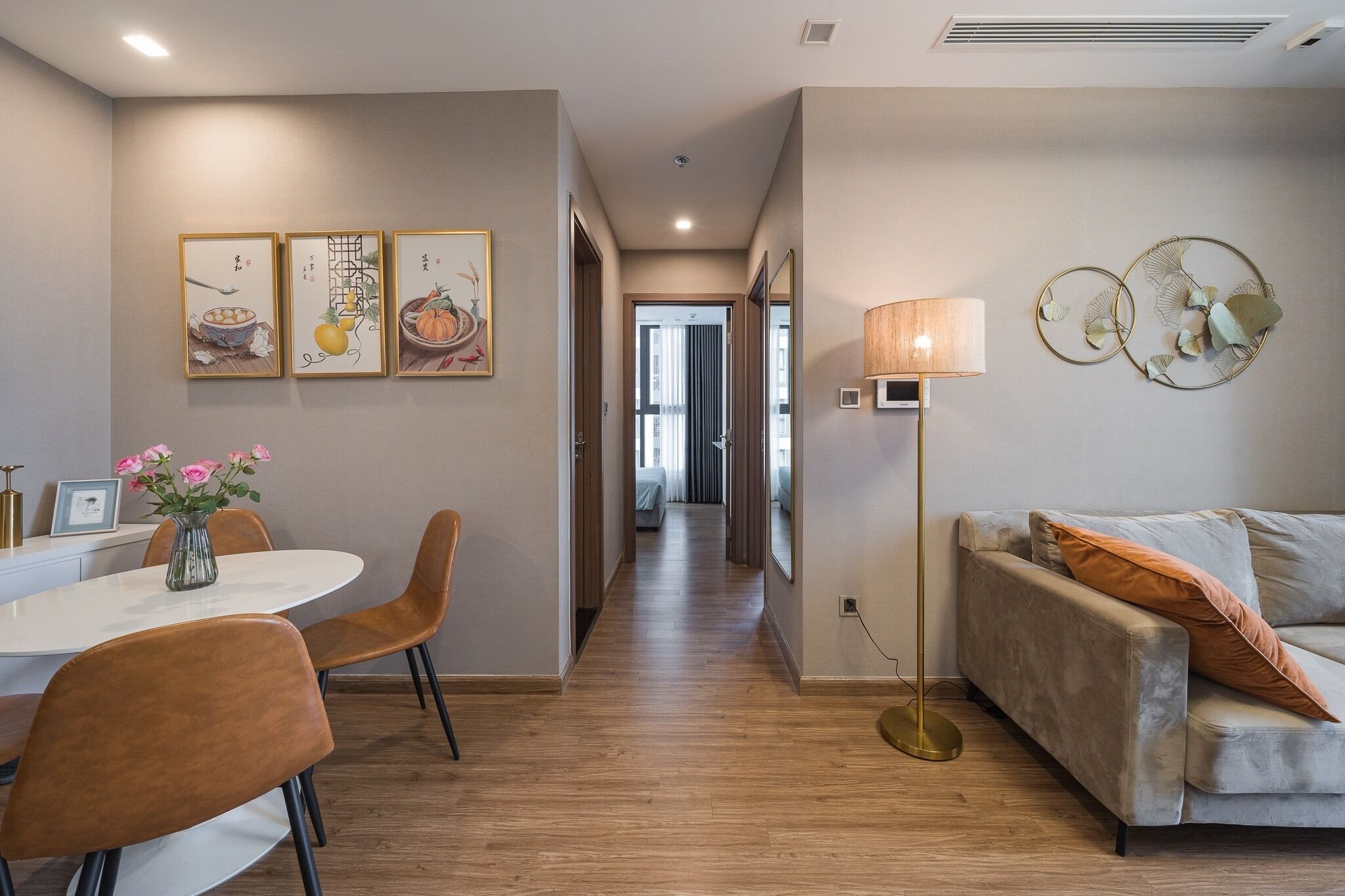 A modern hotel room with a dining area, a sofa, and artwork on the walls.