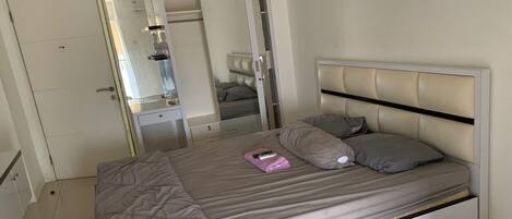 A bedroom with a bed, a wardrobe, and a mirror.