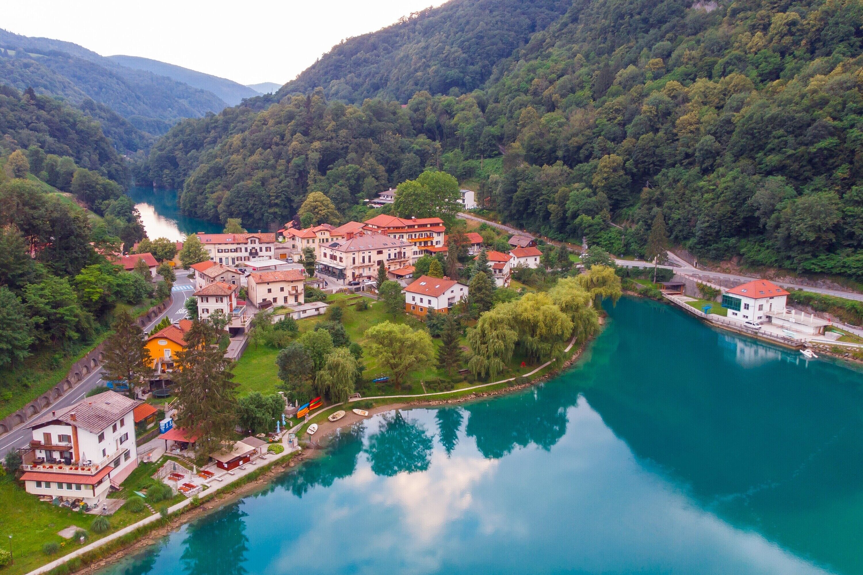 A riverside town with buildings along the water, surrounded by forested hills.