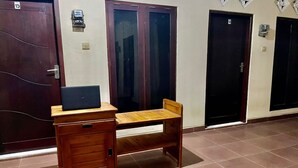 Una habitación con un escritorio de madera, una silla y una computadora portátil. Hay tres puertas, cada una con un número encima.