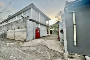Un edificio con puerta roja, pared de hormigón y fachada gris.