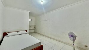Una habitación pequeña y limpia con una cama individual, un espejo y una lámpara en el techo.