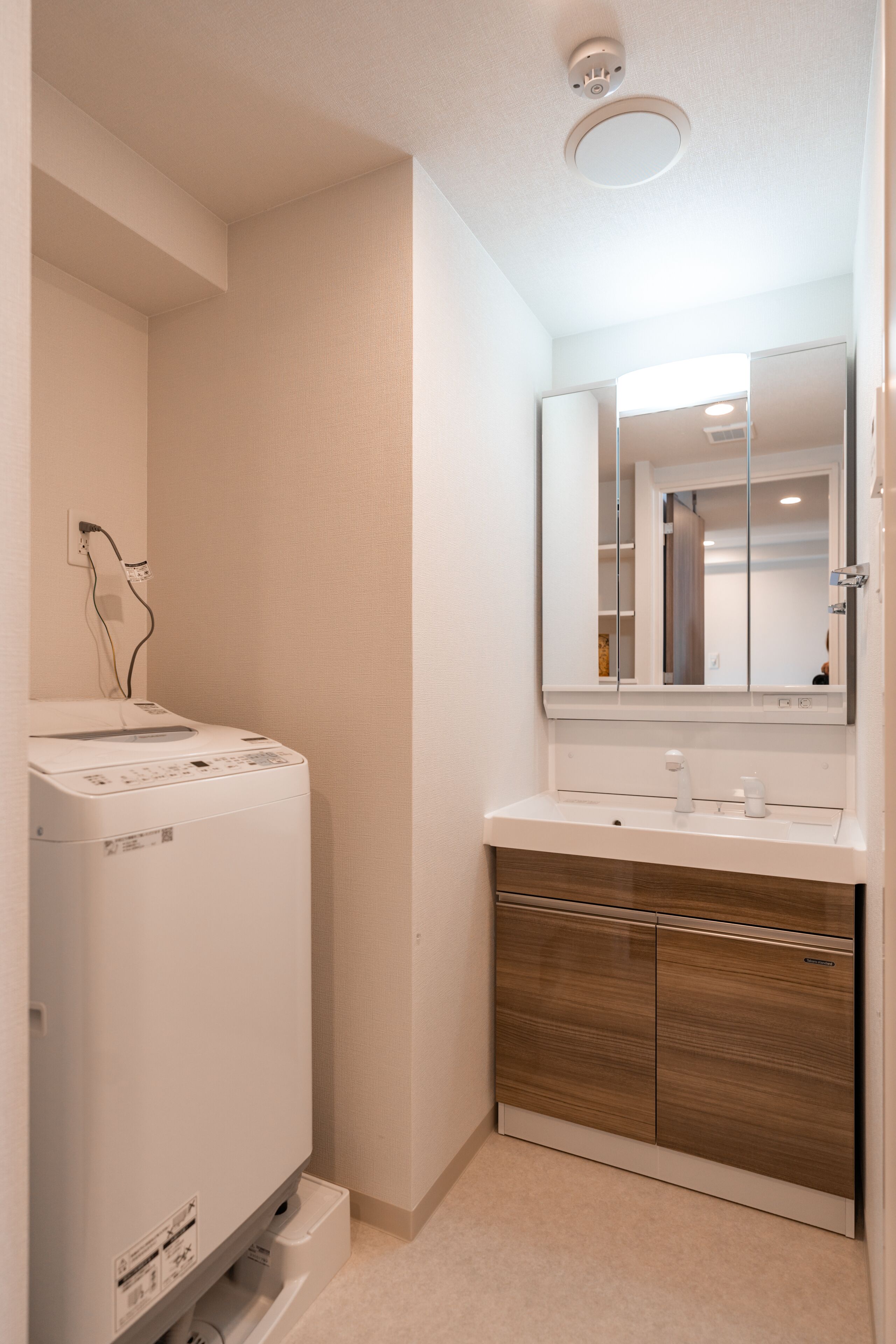 Casa de banho compacta com máquina de lavar roupa, lavatório e espelho.