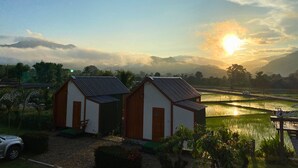A rural landscape with two small buildings, a parked car, and a field of crops. - Hinpha homestay (Pua)