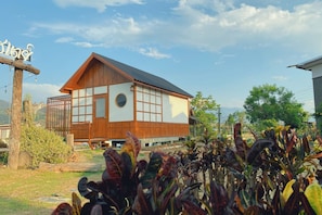 A traditional wooden building with large windows and a sloped roof, surrounded by greenery. - Hinpha homestay (Pua)