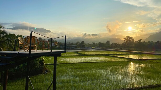 A terrace with wicker chairs overlooking terraced rice fields and a sunrise or sunset in the background. - Hinpha homestay (Pua)