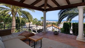 A terrace with a sofa, a small table, and a view of the sea and palm trees. - Relax - Denia, Costa Blanca (Denia)