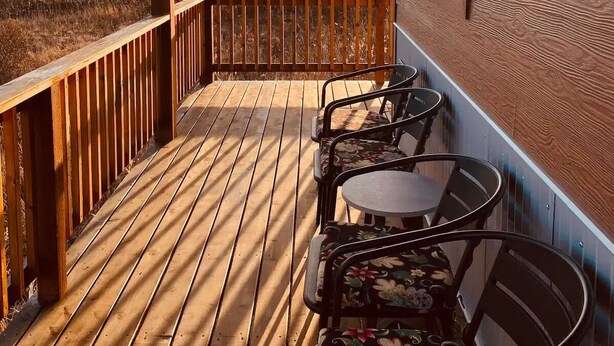 A wooden deck with a railing, a table, and four chairs. - Alpine Meadows Cabin

 (Homer)
