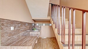 A modern kitchen with a marble backsplash, a built-in sink, and a staircase with metal railings. - OYO Life 93497 Griya Kost Rr (Salatiga)